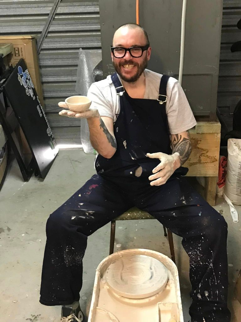 Mike holding a poorly made clay pot after spending a few hours at a pottery wheel for the first time.